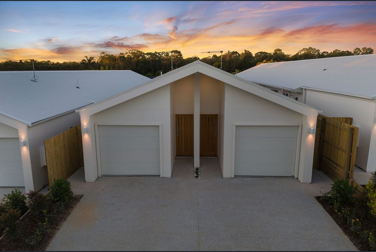 A couple of white garage doors on top of a driveway.