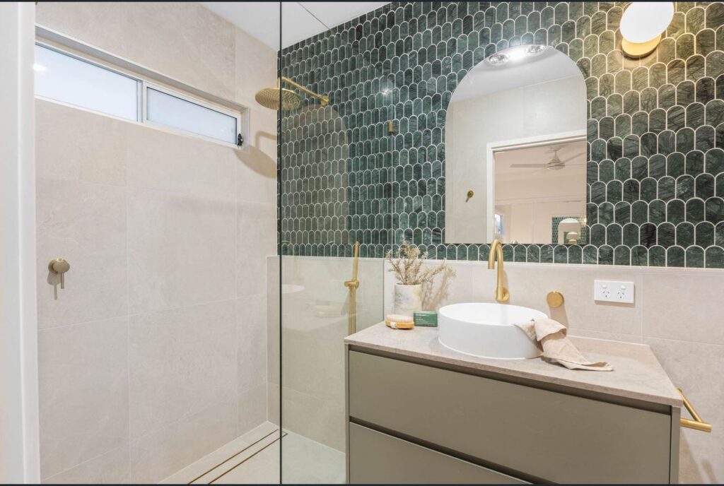 A bathroom with a sink, mirror and shower.