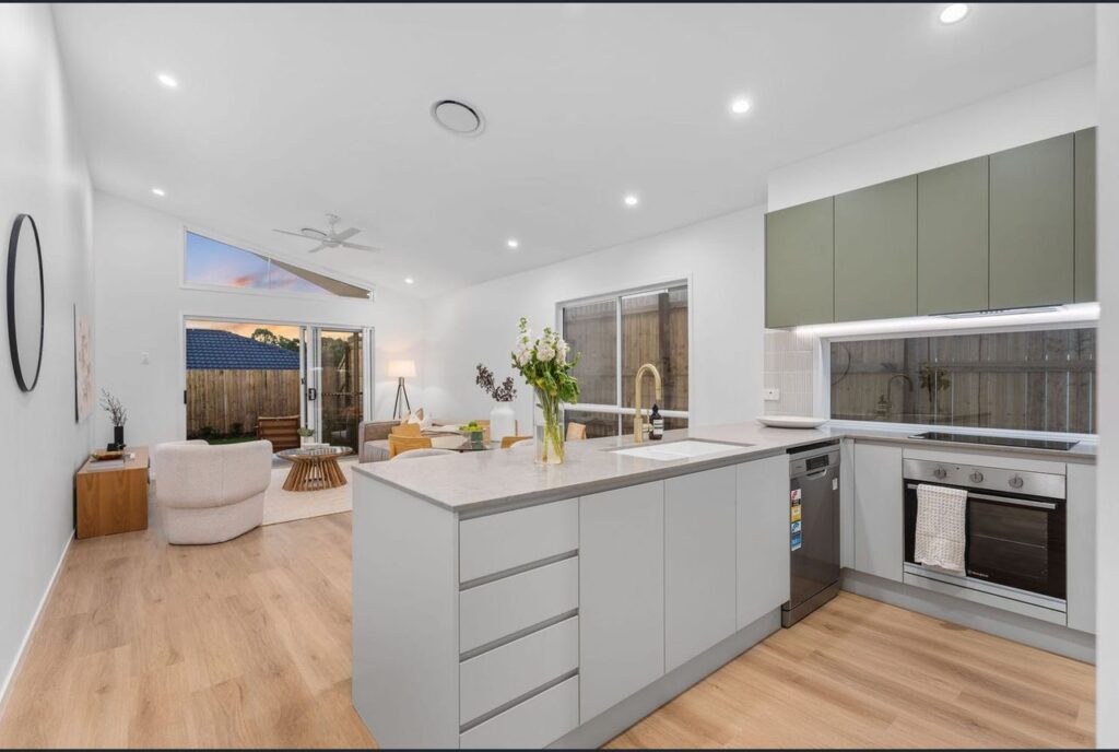 A kitchen with white cabinets and wooden floors