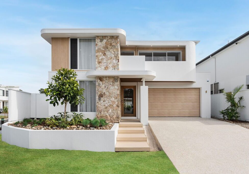 A modern house with a stone wall and white trim.